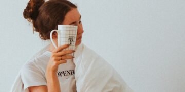 woman in white robe holding white ceramic mug